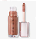 Brillo labial FENTY BEAUTY Gloss Bomb de Mi tienda en tono metálico cálido con destellos dorados y aplicador grande.