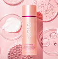 Crema corporal antiedad Mi tienda Kopari Ultra Renewal Retinol en envase rosa con textura cremosa sobre fondo rosado